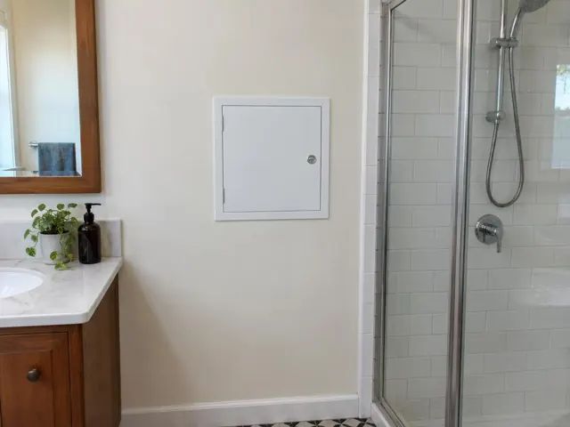 Small access panel on a bathroom wall beside a tiled shower and vanity in Toronto